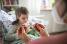 Παιδί με μάσκα και άτομο που του μετρά τη θερμοκρασία