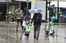 Πατέρας και γιος περπατούν στην Αθήνα εν μέσω βροχής 