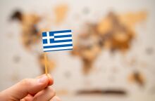 Ελληνικό σημαιάκι μπροστά σε έναν παγκόσμιο χάρτη