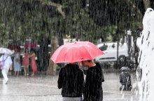 Πολίτες με ομπρέλες προστατεύονται από τη βροχή