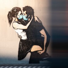 Stencil όπου απεικονίζεται αγόρι να φιλά κορίτσι με χειρουργικές μάσκες
