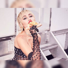 Η τραγουδίστρια Miley Curys με ένα κομμάτι πίτσα στο χέρι της