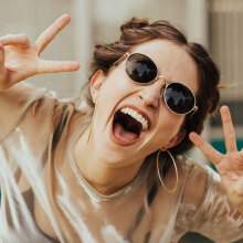 Κοπέλα με γυαλιά ηλίου που γελάει στην κάμερα
