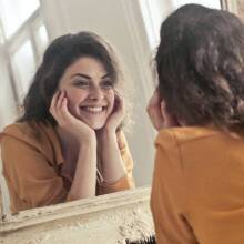 Κοπέλα που κοιτάει στον καθρέφτη και χαμογελάει