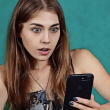 Γυναίκα κοιτάει σοκαρισμένη το κινητό της