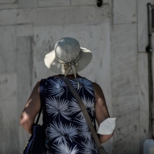 Γυναίκα με γυρισμένη πλάτη στον φακό και τη μάσκα προστασίας από τον κορωνοϊό αφημένη στον αγκώνα