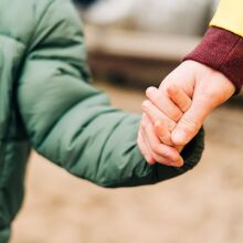 Ένας γονιός που κρατάει το παιδί του από το χέρι