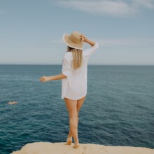 Γυναίκα με καπέλο μπροστά στη θάλασσα