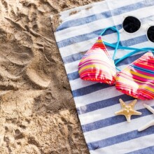 Μαγιό, γυαλιά ηλίου και αστερίες σε πετσέτα θαλάσσης στην άμμο