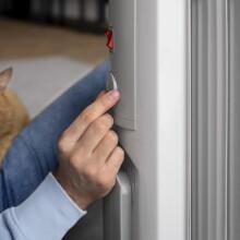 Άνδρας ρυθμίζει τη θέρμανση στο καλοριφέρ αγκαλιά με τη γάτα