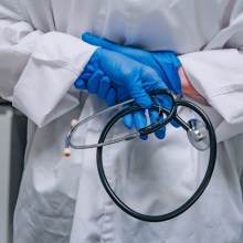 Γιατρός κρατά στηθοσκόπιο και φορά γάντια στα χέρια του