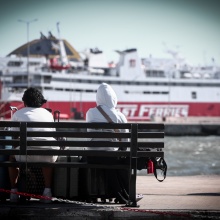 Πλοίο και πολίτες καθισμένοι σε παγκάκι στο λιμάνι του Πειραιά