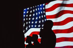 Φιγούρεα ανθρώπων μπροστά από τη σημαία της Αμερικής