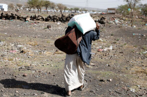 Άνδρας στην Υεμένη κουβαλά στην πλάτη ένα σακί με τρόφιμα έξω από καταυλισμό προσφύγων στην πρωτεύουσα Σαναά