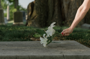 Χέρι που επαναποθέτει λουλούδια σε τάφο