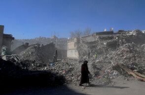 Γυναίκα ντυμένη στα μαύρα μπροστά από ισοπεδωμένα κτίρια στην πολη Καχραμανμαράς μετά τον σεισμό στην Τουρκία