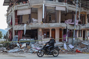 Νεαρός στην πόλη Χατάι περνά με το μηχανάκι μπροστά από κτίριο που έχει υποστεί ζημιές από τον σεισμό στην Τουρκία