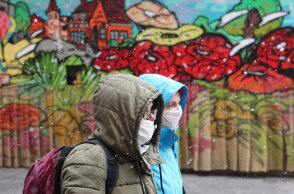 Άνθρωποι με μάσκα για τον κορωνοϊό μπροστά από mural για την πανδημία covid στο Σεράγεβο