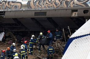 Πυροσβέστες απομακρύνουν τη σορό επιβάτη μετά τη σύγκρουση τρένων στα Τέμπη