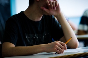 Μαθητής αναμένει στο θρανίο του για τα θέματα των εξετάσεων κρατώντας το στιλό στο χέρι