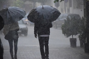 Δύο άτομα με ομπρέλες εν μέσω καταιγίδας