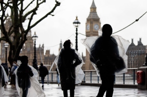 Κάτοικοι του Λονδίνου με αδιάβροχα μπροστά από το Παλάτι του Ουεστμίνστερ