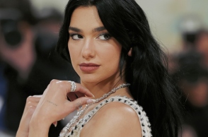 Η Dua Lipa σε κοντινό πλάνο φορώντας άσπρο φόρεμα και κοσμήματα
