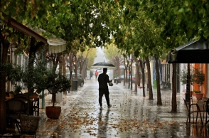 Άνδρας όρθιος με ομπρέλα στη μέση του δρόμου κατά την διάρκεια βροχής