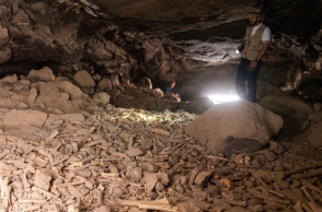 Αρχαιολόγος σε σπηλιά εξετάζει οστά