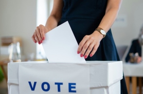 Γυναικεία χέρια ρίχνουν ψηφοδέλτιο σε κάλπη που γράφει vote