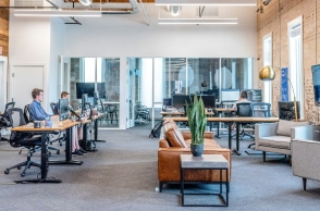 Αίθουσα με τραπέζια, καρέκλες, γραφεία, εργαζόμενους, γλάστρα