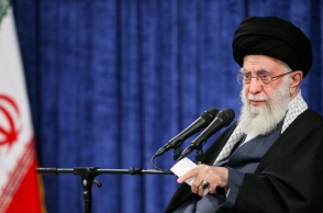 άνδρας με γενειάδα καθιστός, μικρόφωνο, σημαία