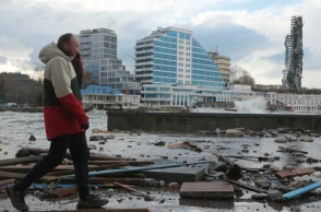 ανδρας περπαταει μπροστα απο κατεστραμμενα κτηρια