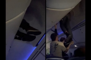 εσωτερικο αεροπλανου, επιβατες βοηθουν ανδρα να ξεκολλησει απο ντουλάπι χειραποσκευών