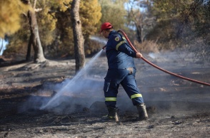 Πυροσβέστης με τη μάνικα ανά χείρας επιχειρεί για την κατάσβεσης φωτιάς
