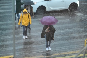 Πολίτες με ομπρέλες εν μέσω καταιγίδας σε δρόμο της Αθήνας