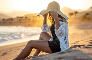 Γυναίκα με ψάθινο καπέλο κάνει διακοπές στην παραλία