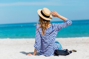 Γυναίκα με ψάθινο καπέλο στην παραλία