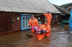 Mέλη του ρωσικού Υπουργείου Έκτακτης Ανάγκης μεταφέρουν ένα παιδί από πλημμυρισμένο σπίτι 