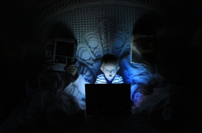 παιδι μπροστα σε laptop μαζί με 2 γονείς