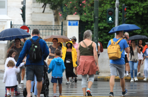Πολίτες με ομπρέλα περπατούν εν μέσω βροχοπτώσεων