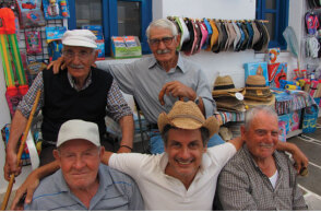 Ο Dimitris Dassios καθισμένος στο παγκάκι ανάμεσα σε φίλους στο νησί