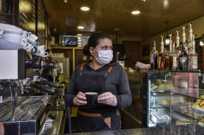 Γυναίκα με προστατευτική μάσκα και γάντια σε καφέ