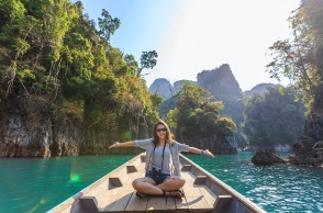 Κοπέλα κάθεται σε βάρκα με τα χέρια ανοιχτά