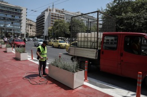 Εργάτης του δήμου ποτίζει λουλούδια σε ζαρντινιέρα στον "Μεγάλο Περίπατο" στο κέντρο της Αθήνας 