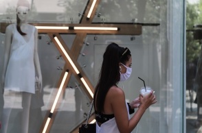 Μία κοπέλα με μάσκα και καφέ