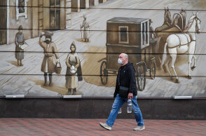 Κορωνοϊός στη Ρωσία: Άνδρας με προστατευτική μάσκα περνά μπροστά από γκράφιτι σε δρόμο της Μόσχας