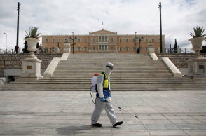 Υπάλληλος του Δήμου Αθηναίων στην πλατεία Συντάγματος με προστατευτική στολή για τον κορωνοϊό
