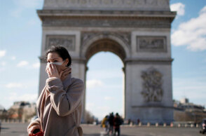 Γυναίκα με μάσκα για τον κορωνοϊό στο Παρίσι με φόντο την Αψίδα του Θριάμβου