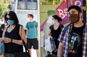 Πολίτες που φορούν μάσκες στη στάση του λεωφορείου